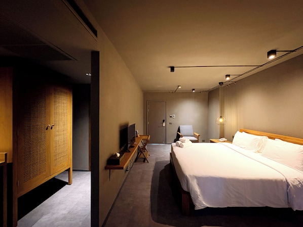Une chambre d’hôtel comprenant un lit, un bureau, une chaise, une armoire et un téléviseur.