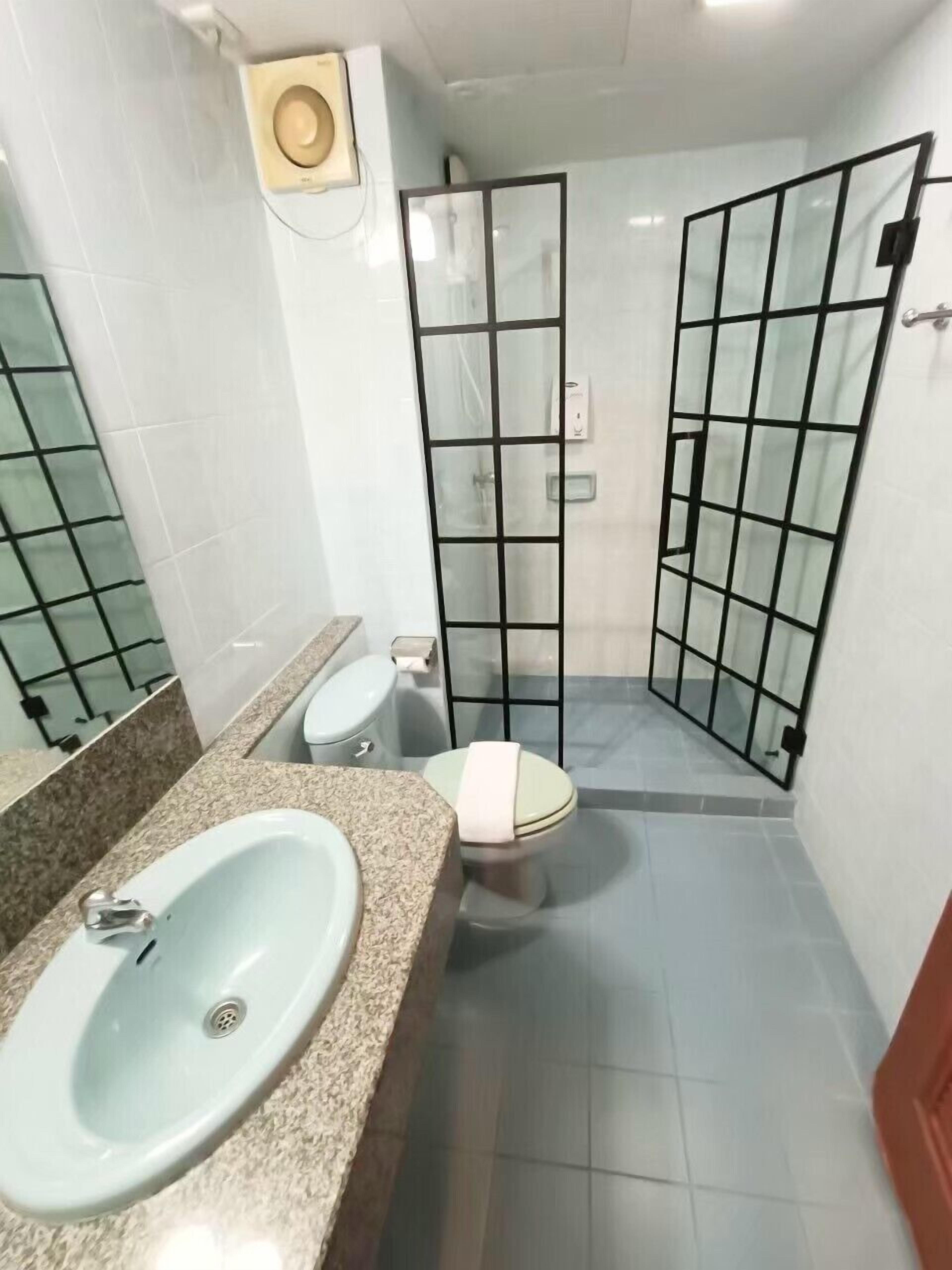 A bathroom with a granite countertop sink, a toilet, and a shower enclosure with frosted glass doors.