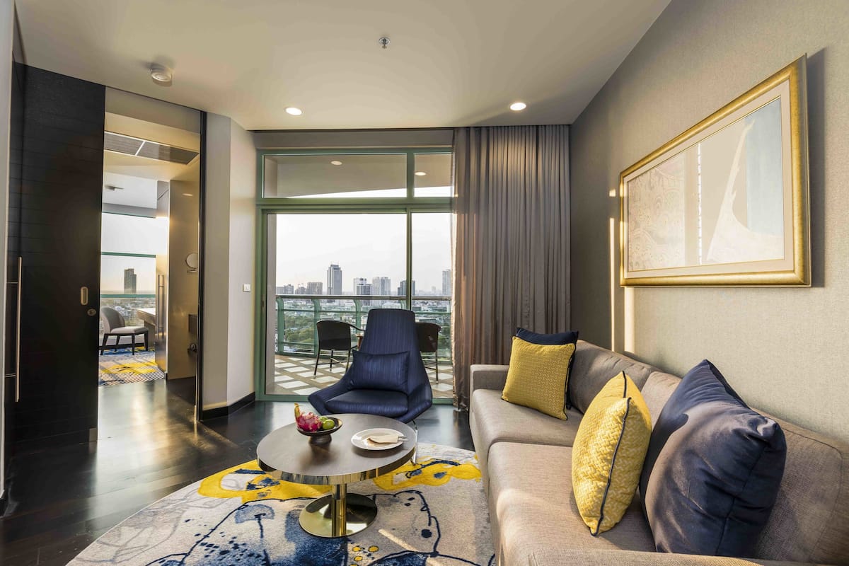 Un salon moderne avec un canapé, une table basse et une vue sur la ville grâce à de grandes fenêtres.