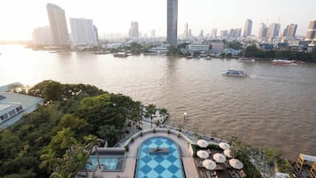 Un hotel moderno de gran altura con piscina y tumbonas, con vista a un río y barcos.