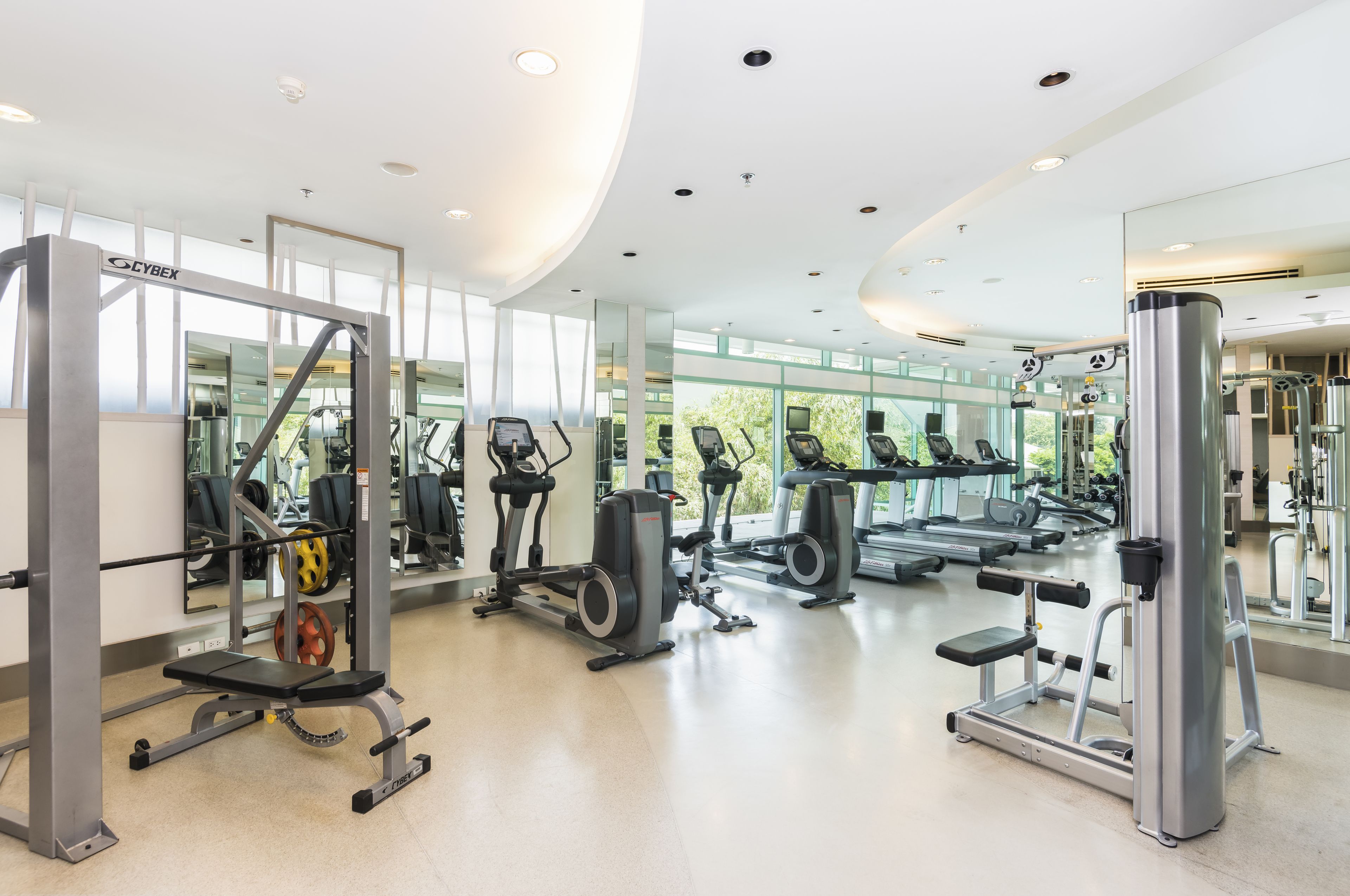 Un gimnasio moderno con diverso equipo de ejercicio, ventanas amplias y una distribución limpia y espaciosa.