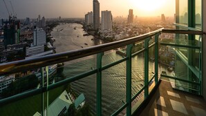 Un paisaje urbano con un río, rascacielos y un balcón que ofrece vistas a la puesta de sol.