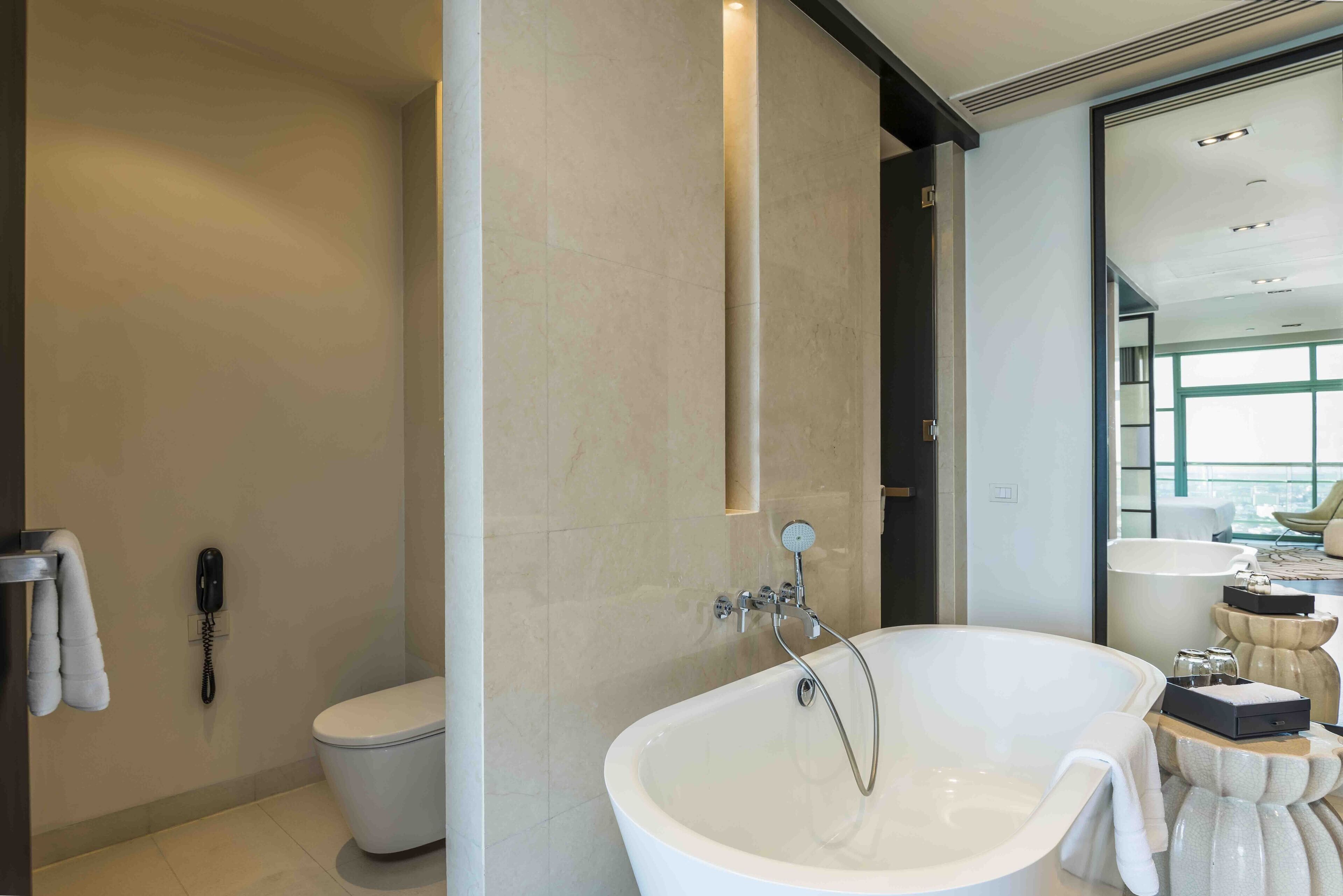 A modern bathroom with a freestanding bathtub, a toilet, and a telephone.