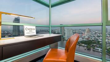 A modern office chair and desk with a laptop and a sign indicating the location as 'Chairium Hotel Riverside-Bangkok'.