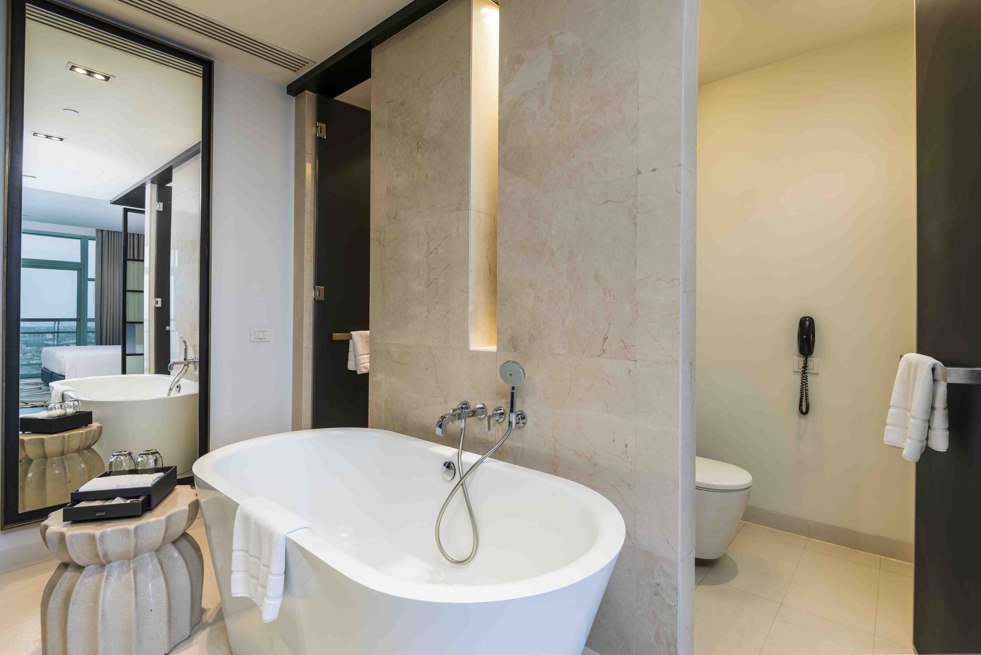 Ein modernes Badezimmer mit einer freistehenden Badewanne, einer Toilette und einem großen Spiegel.