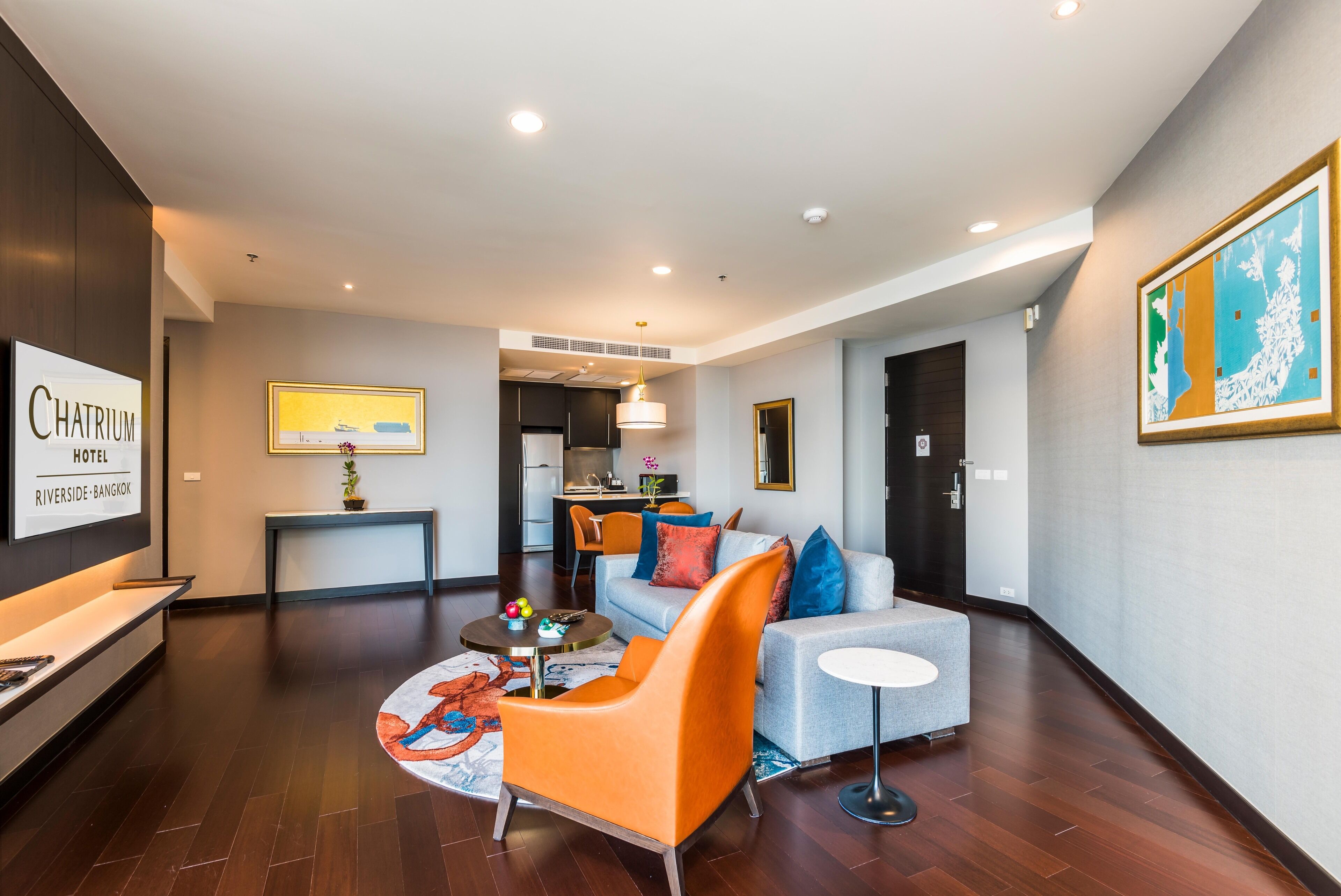 A modern hotel lobby with a sofa, armchair, and a small table with decorative items.
