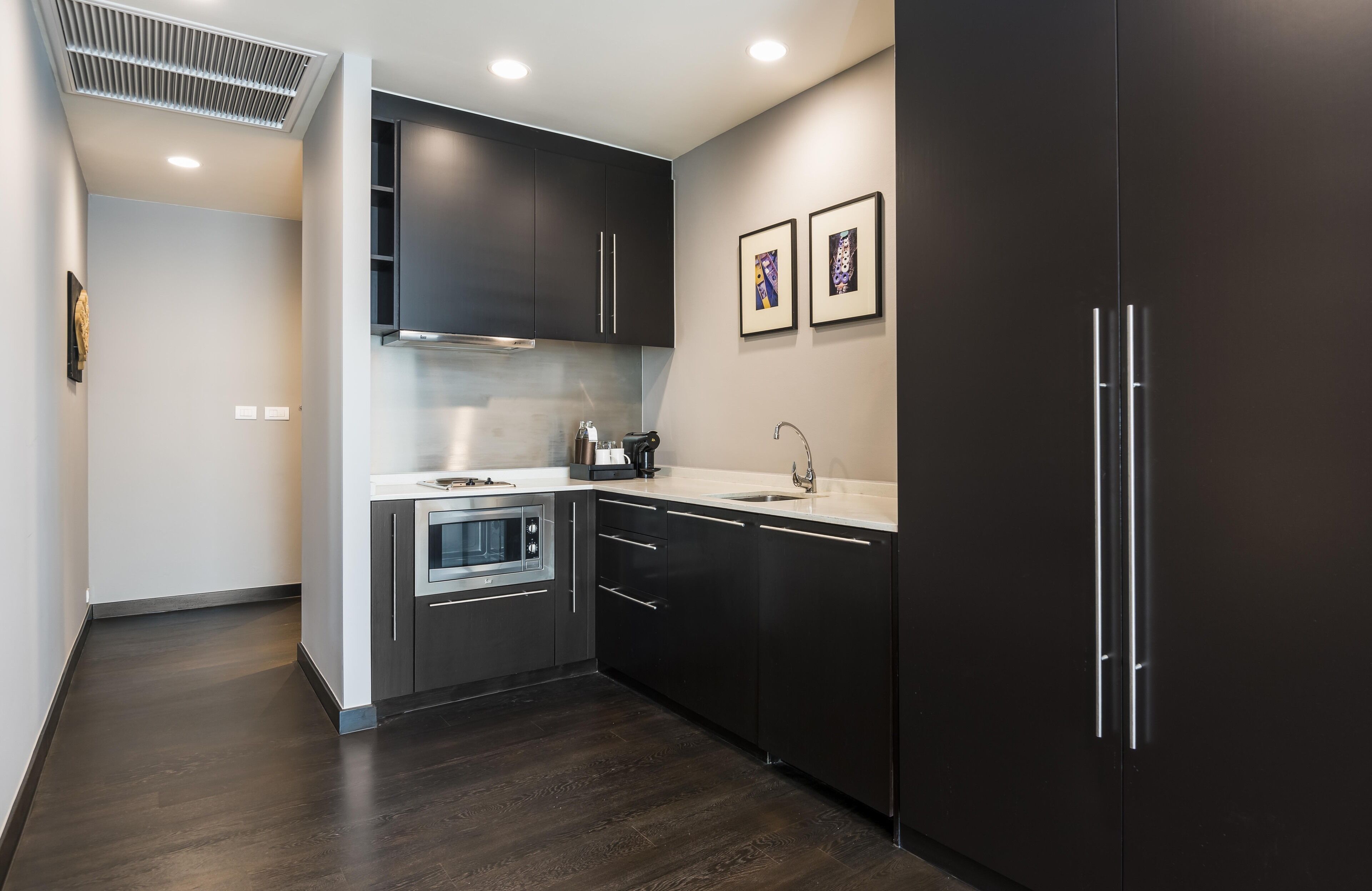 A modern kitchen with dark cabinetry, a stainless steel oven, and a microwave.
