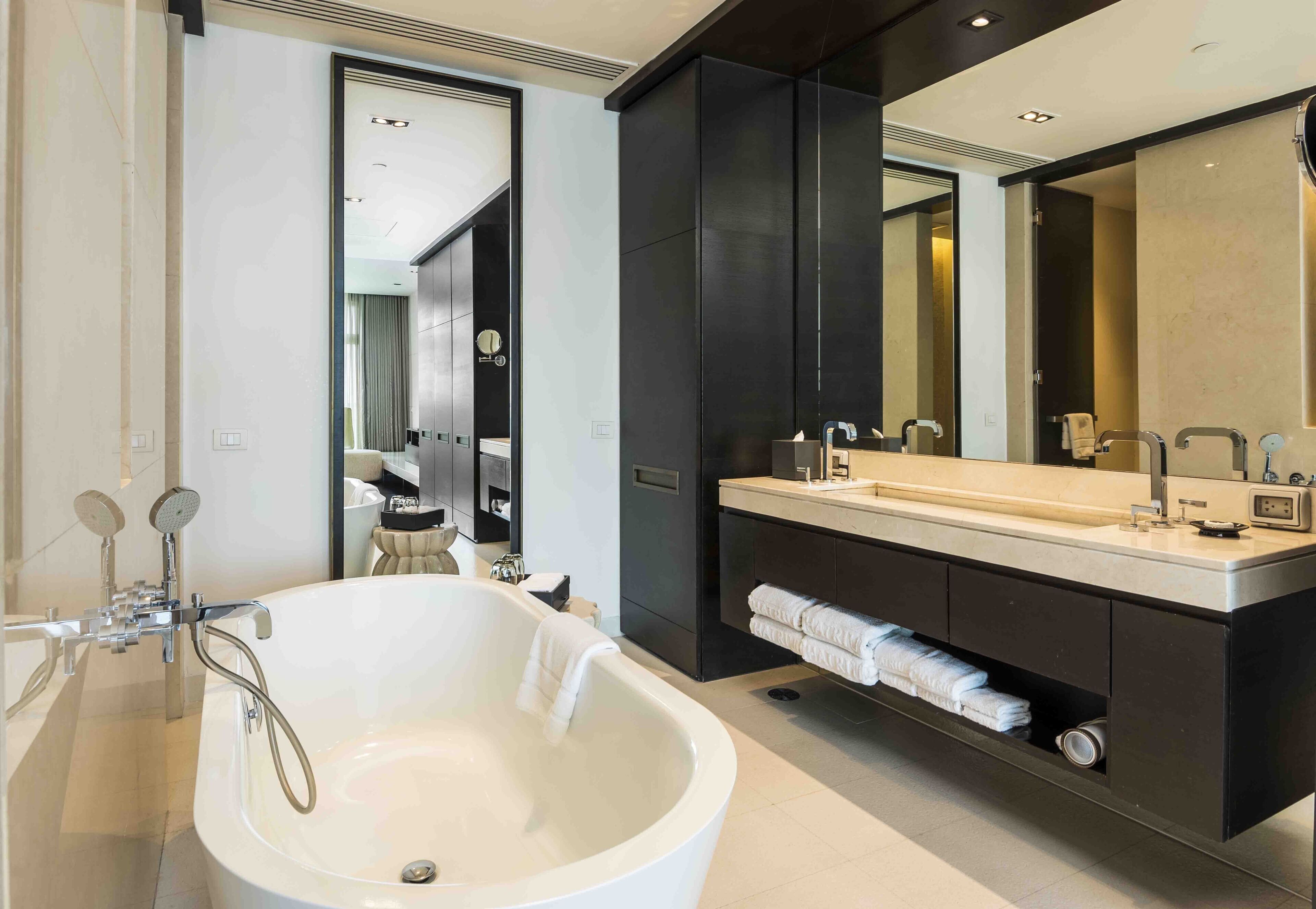 A modern bathroom with a freestanding bathtub, a large mirror, and a vanity with a countertop.
