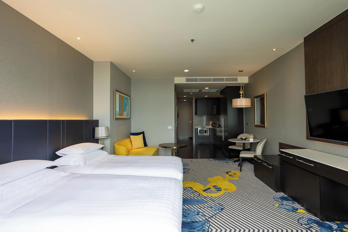 Une chambre d’hôtel avec un grand lit, un petit canapé, un bureau et une kitchenette.