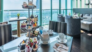Un restaurante en un rascacielos con vistas panorámicas de la ciudad, que presenta una exhibición escalonada de postres y muebles modernos.