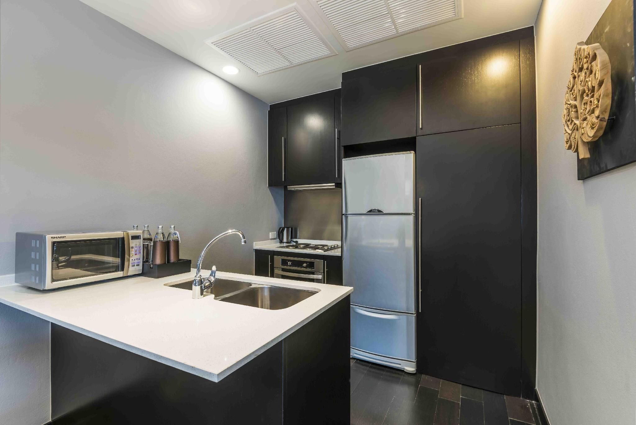 Una cocina moderna con encimera blanca, electrodomésticos de acero inoxidable y armarios oscuros.