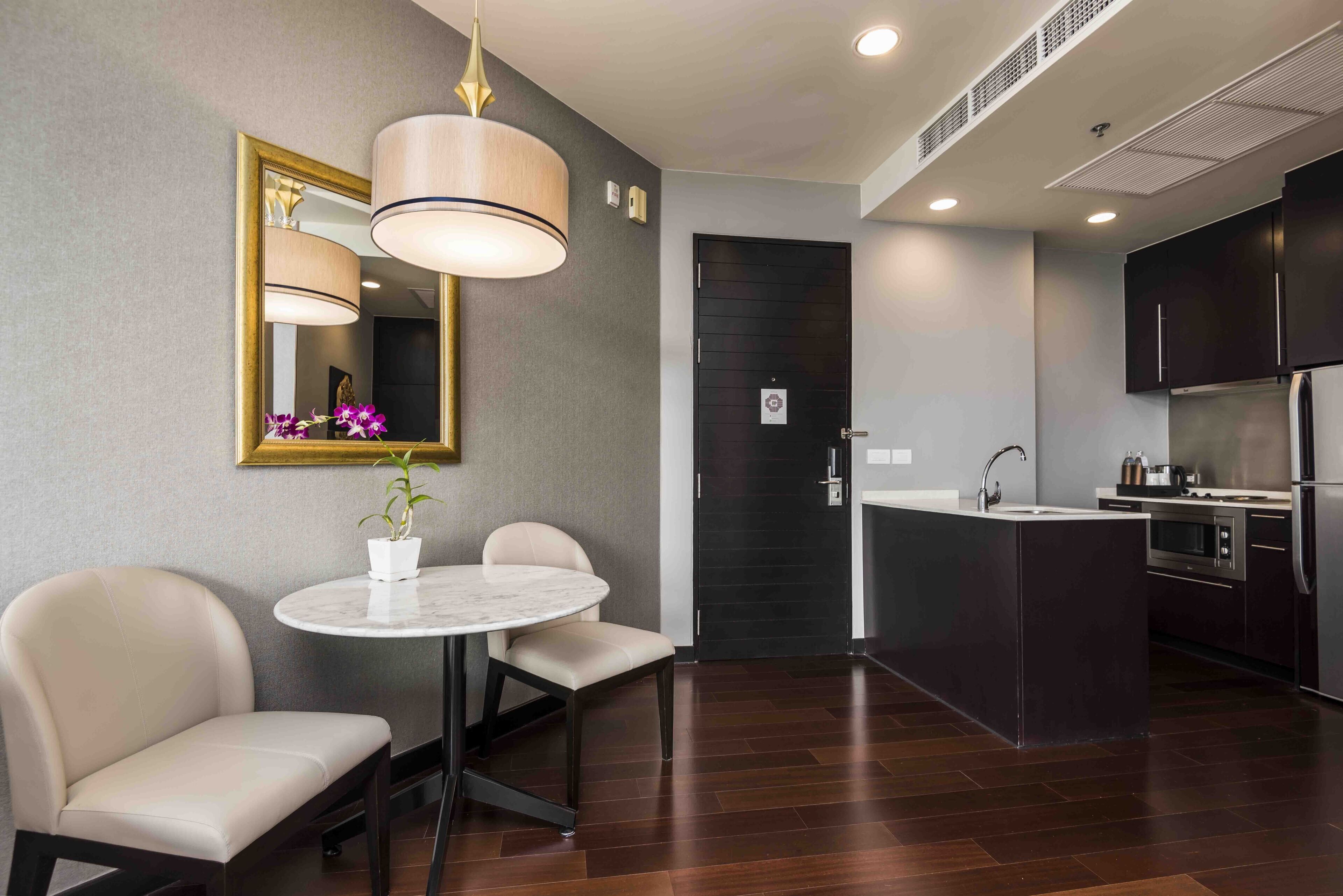 A modern kitchen with dark cabinetry, a central island, and a round dining table with chairs.