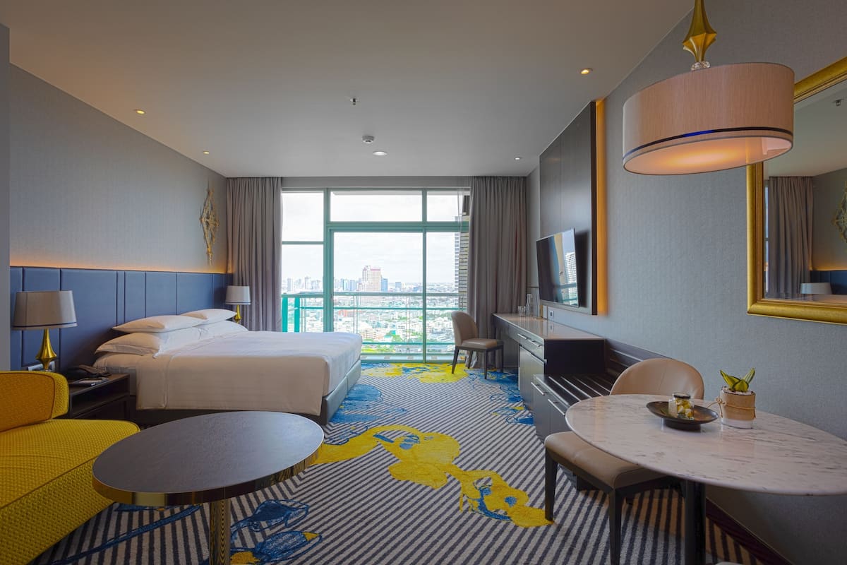 Une chambre d’hôtel avec un lit, un bureau, une chaise, une table ronde et un téléviseur.