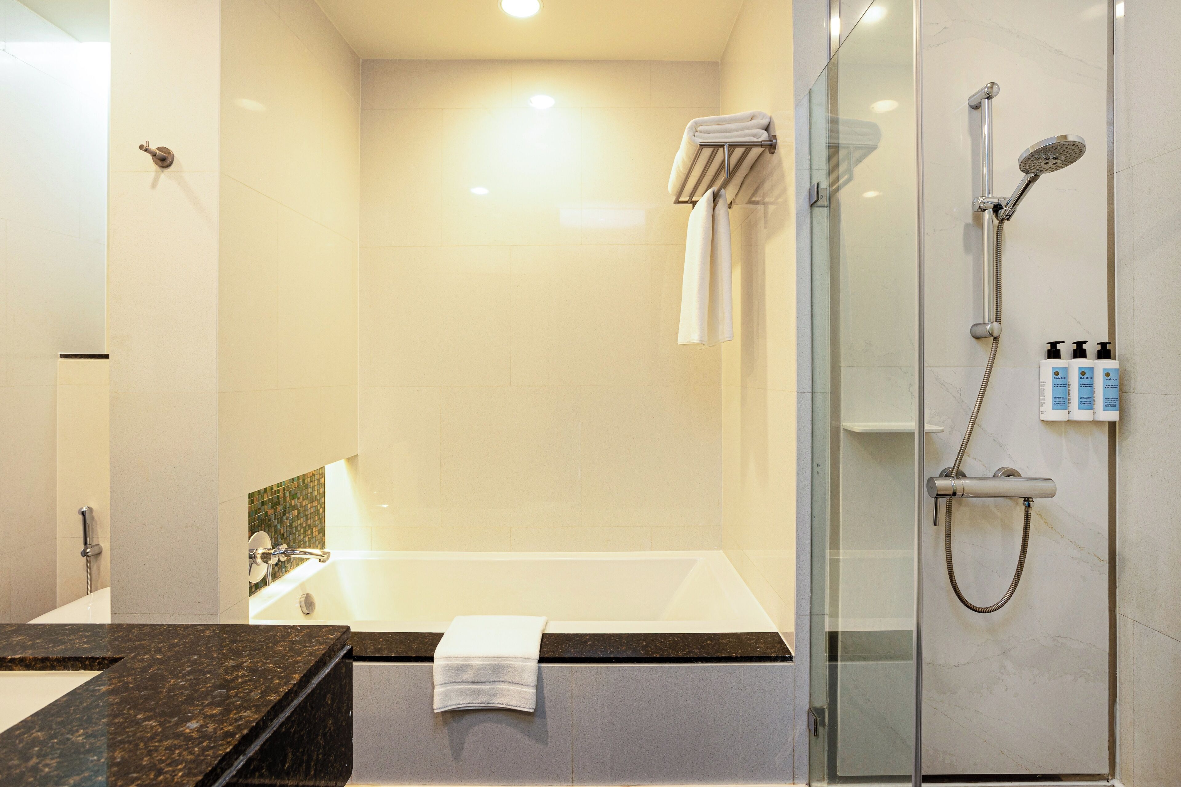 A modern bathroom with a glass-enclosed shower, a bathtub, and a vanity with a marble countertop.