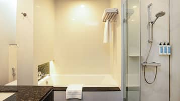 A modern bathroom with a glass-enclosed shower, a bathtub, and a vanity with a marble countertop.