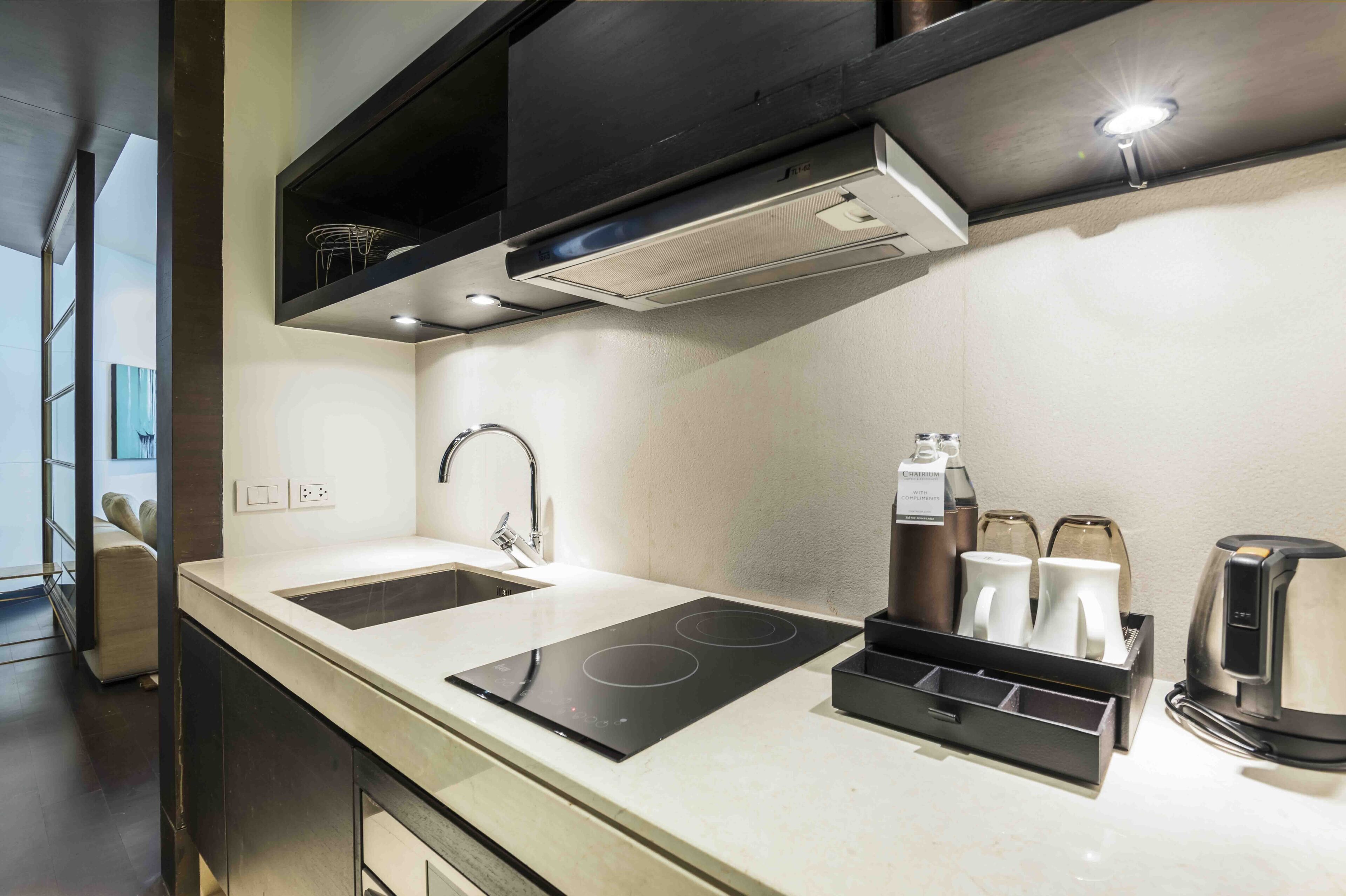 A modern kitchen with two sinks, an induction cooktop, a coffee maker, and a kettle.
