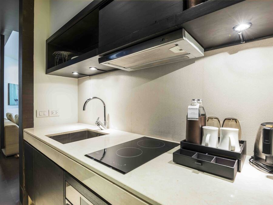 Una cocina moderna con dos fregaderos, una placa de inducción, una cafetera y un hervidor.