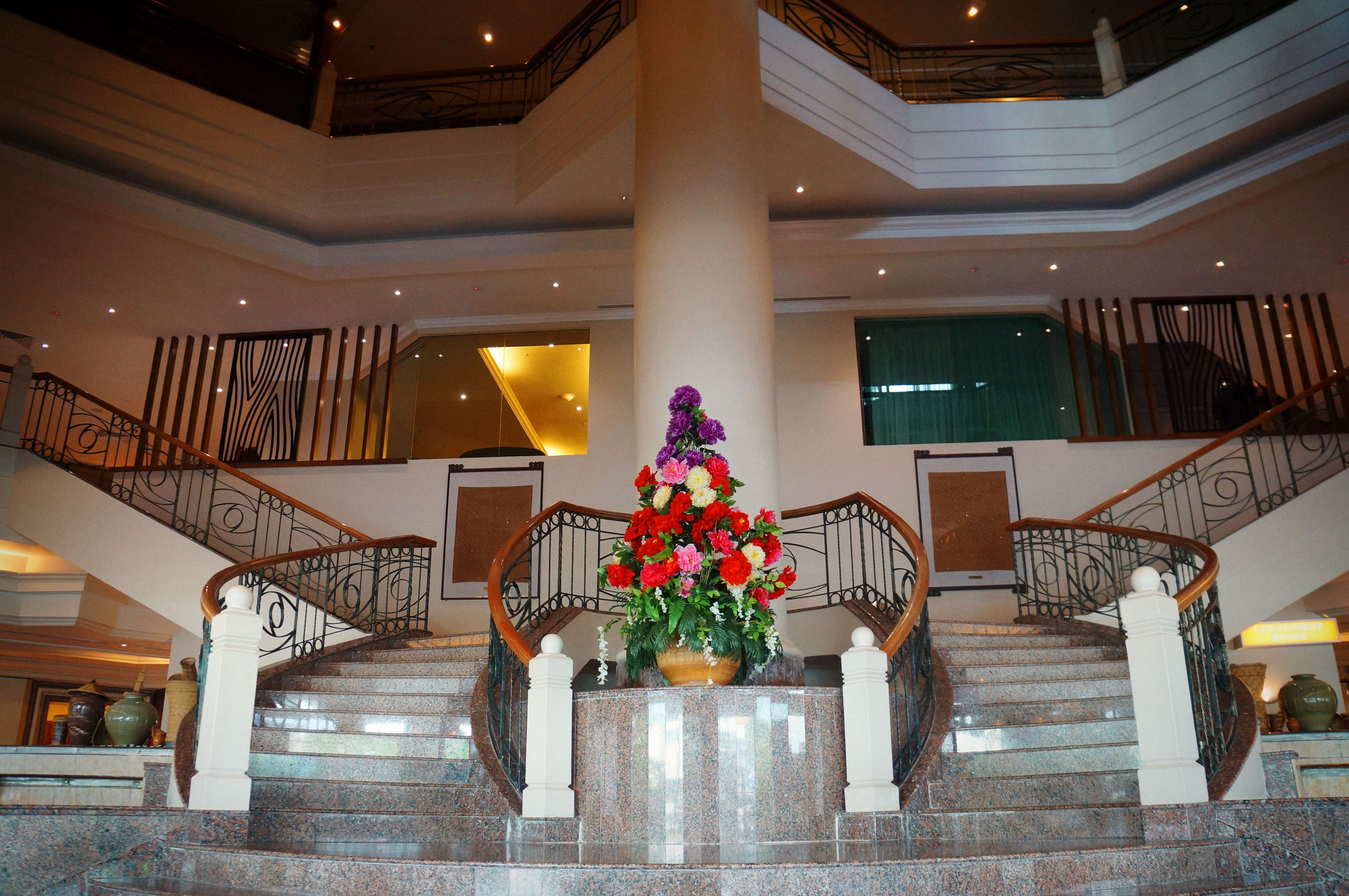 A grand staircase with a floral centerpiece, surrounded by marble steps and ornate railings.