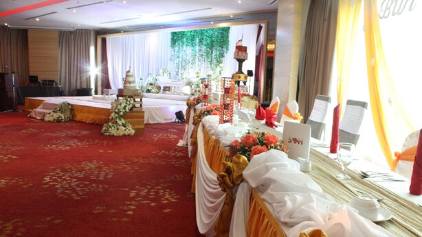 A banquet hall with a red carpet, a stage with floral arrangements, and a long table set for a formal event. - Sabah Oriental Hotel (Kota Kinabalu)