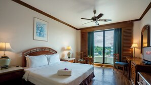 Une chambre d’hôtel avec un grand lit, un ventilateur de plafond, une télévision, un bureau et une vue sur l’extérieur.