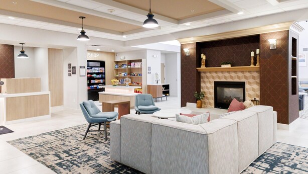 Un moderno vestíbulo de hotel con zona de estar, una tienda y una chimenea.