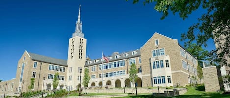 A large institutional building with a prominent tower, multiple windows, and a flag.