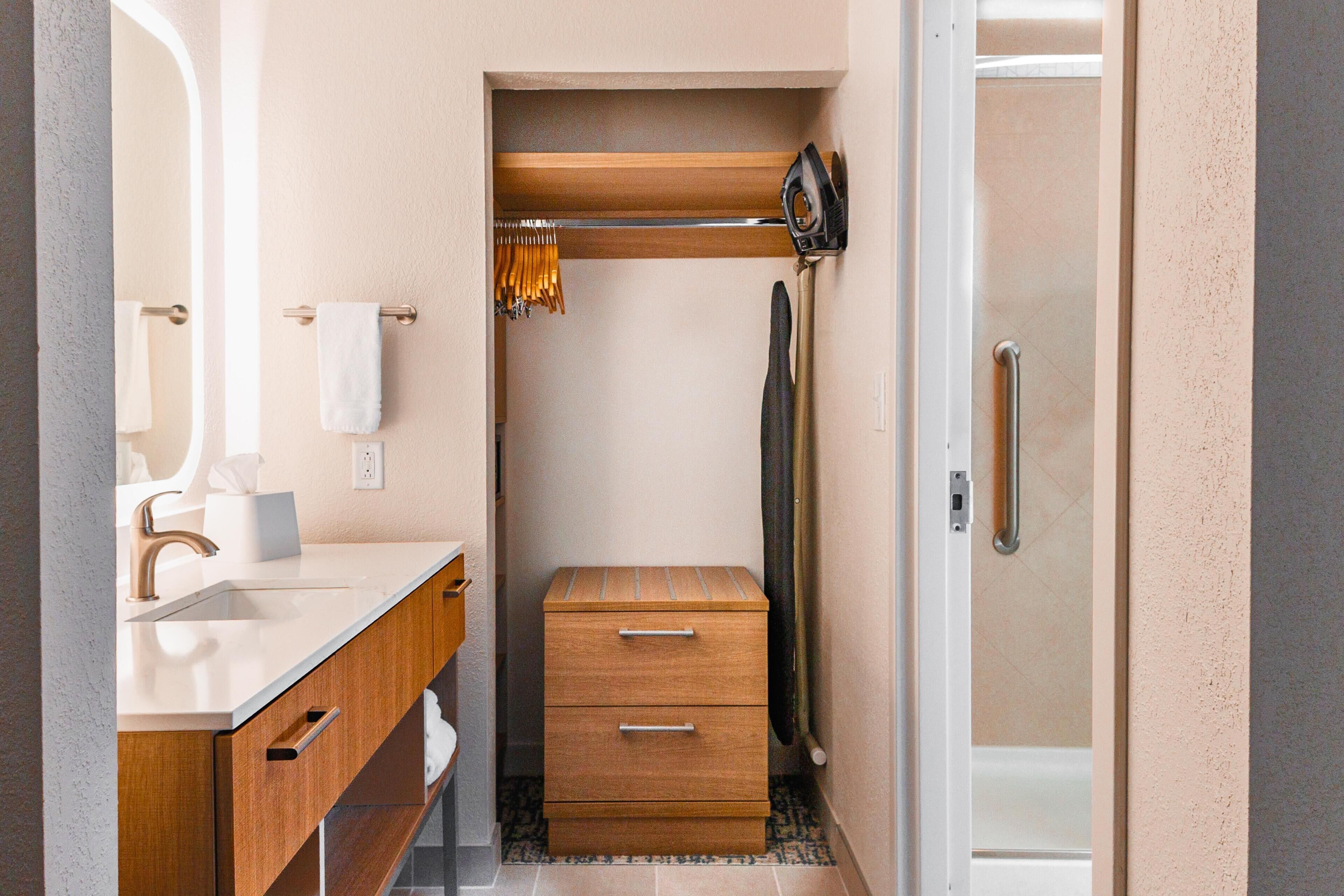 A bathroom with a wooden vanity, a towel rack, a shower area, and a toilet.