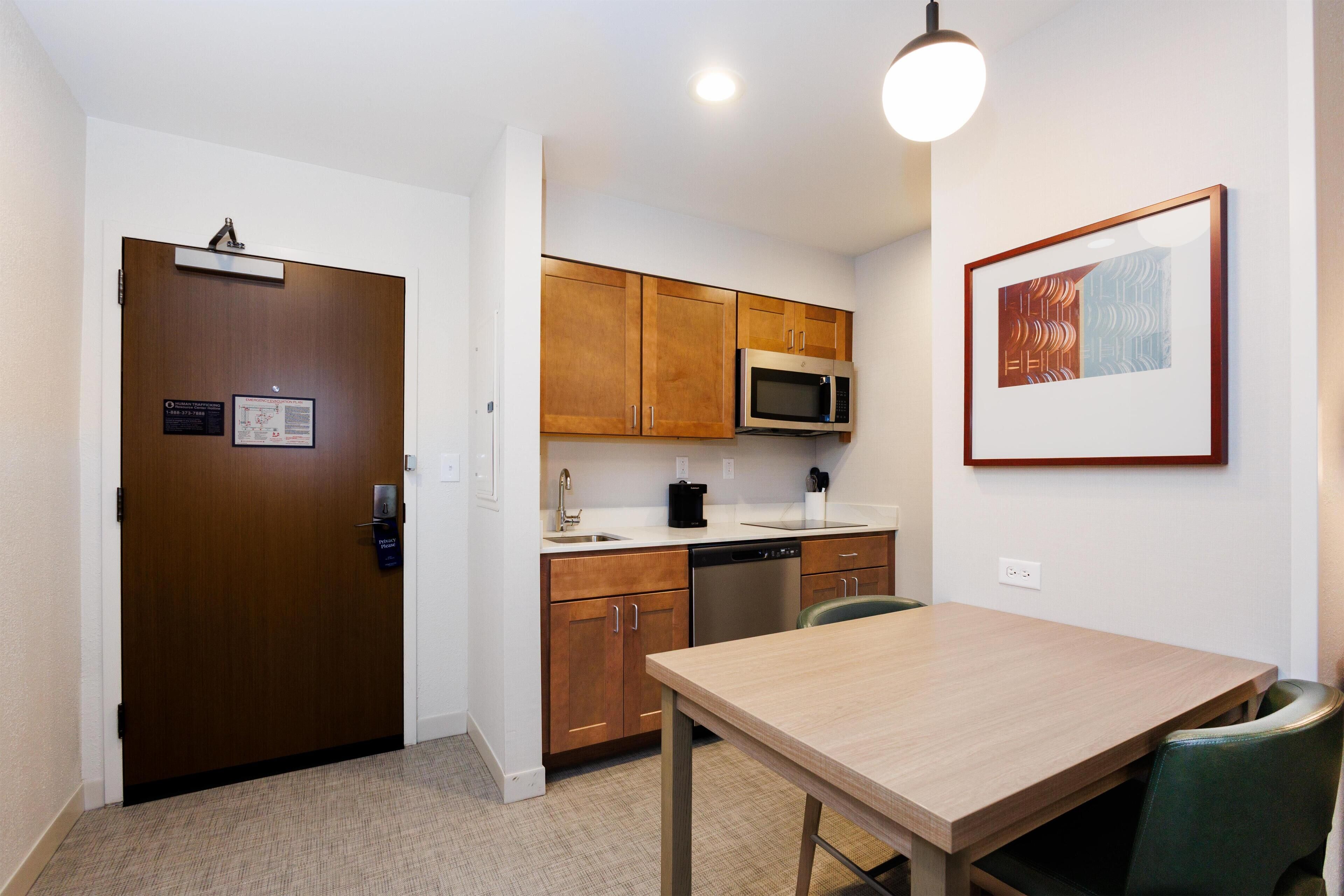 A compact kitchen with wooden cabinets, a microwave, and a dishwasher.