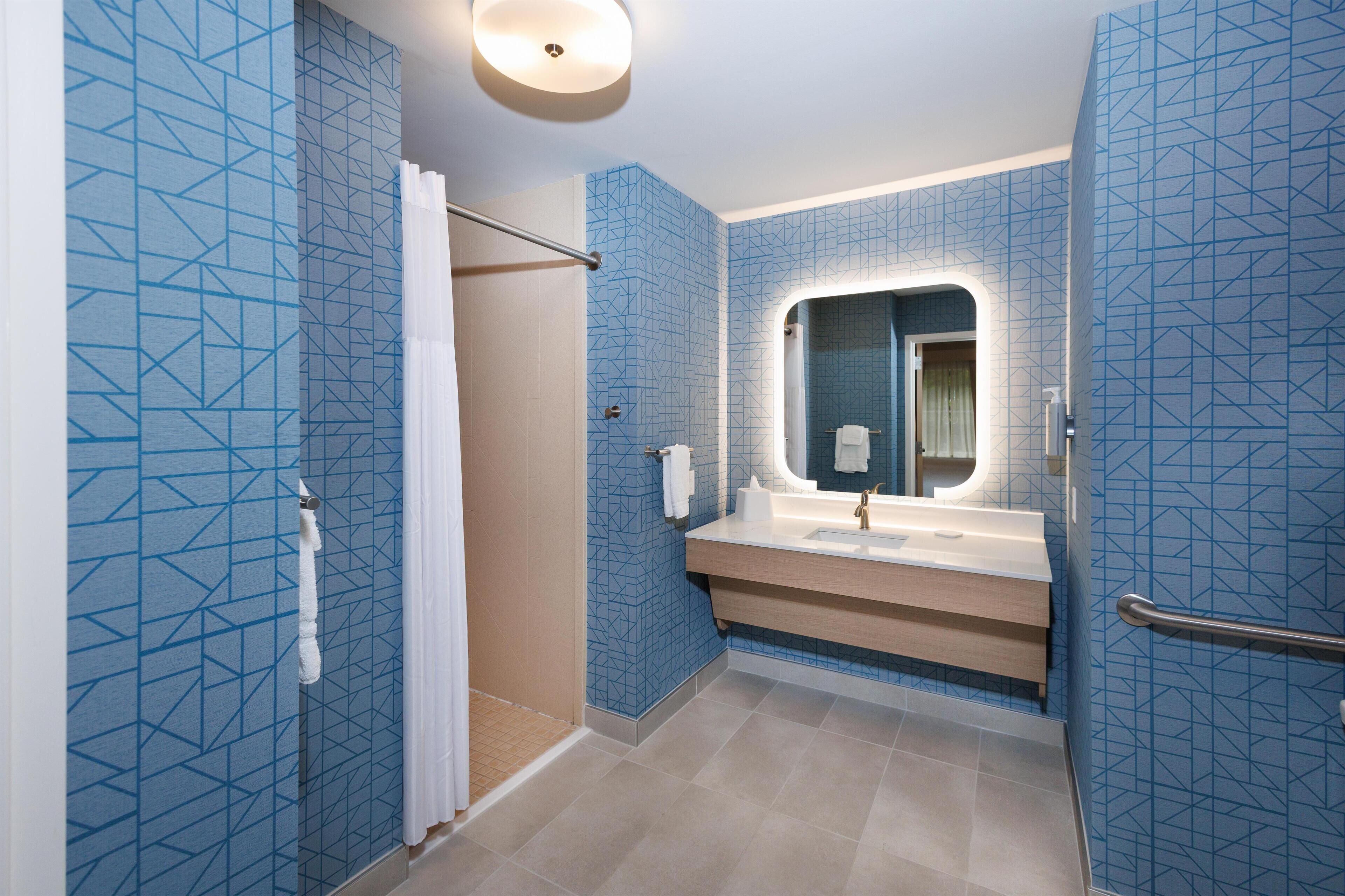 A bathroom with blue patterned walls, a white sink, and a mirror.