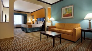 Una habitación de hotel con una cama, un sofá, una mesita de café y un cuadro en la pared.