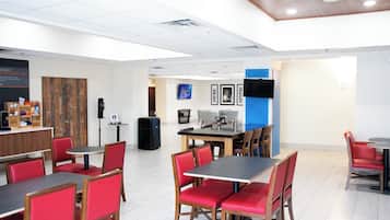 Un comedor moderno con sillas rojas, una mesa de madera y una pared azul decorativa.