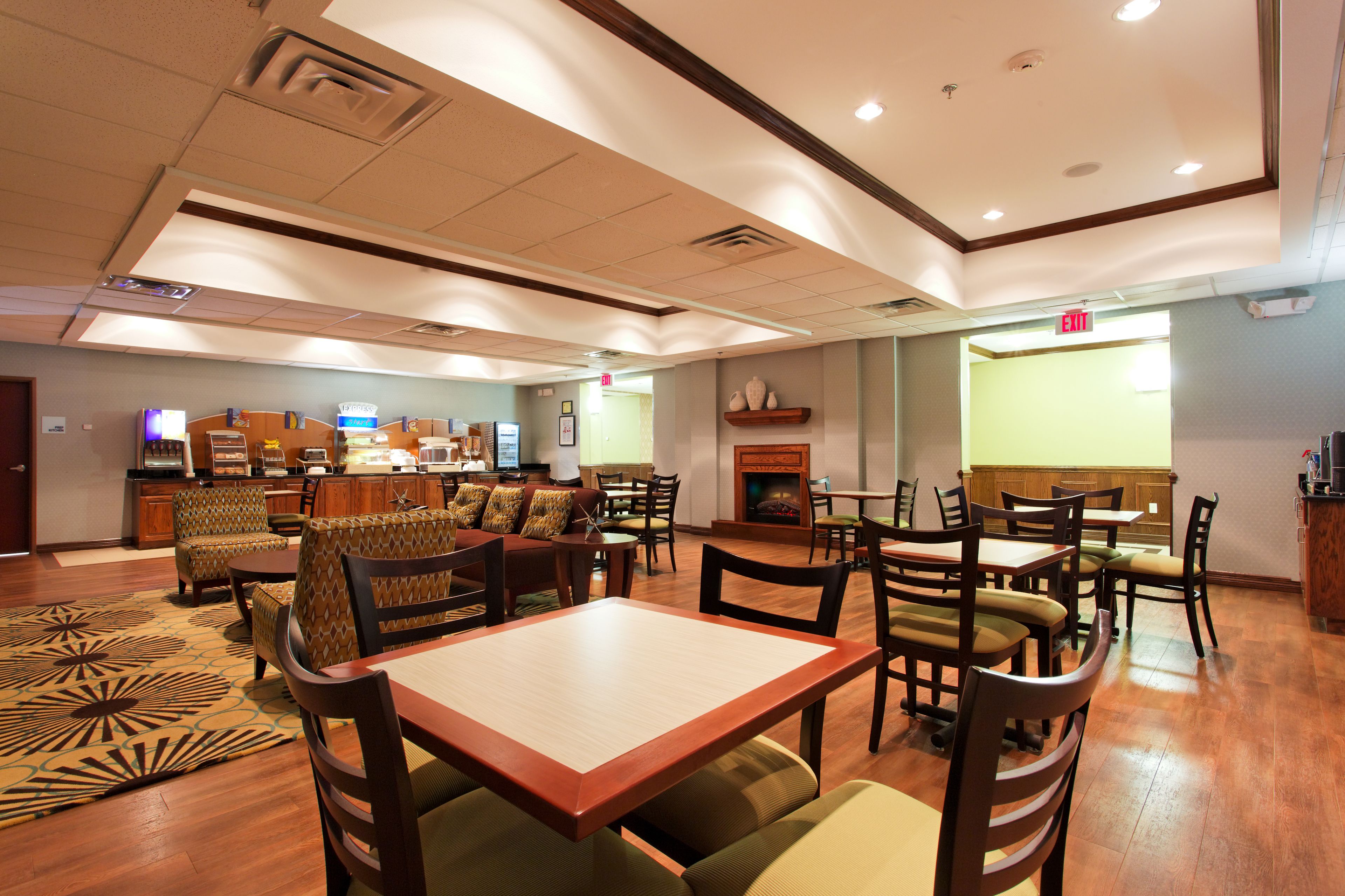 A hotel lobby with a fireplace, dining area, and a reception desk.