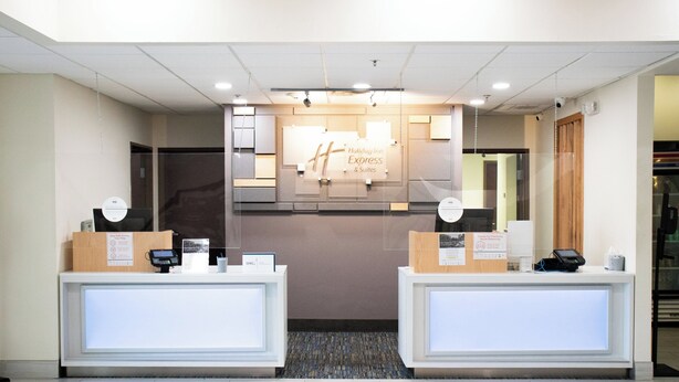 Mostrador de recepción de un hotel con el letrero de Holiday Inn Express & Suites, dos mostradores y un área de recepción.