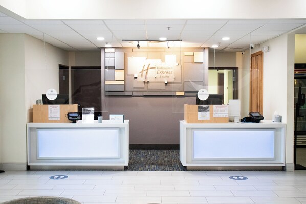 A hotel reception desk with a sign for Holiday Inn Express & Suites, two counters, and a reception area.