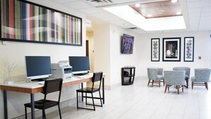 Un espacio de oficina moderno con un mostrador de recepción, computadoras y una zona de estar con sillas.