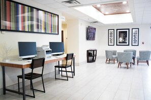A modern office space with a reception desk, computers, and a seating area with chairs.