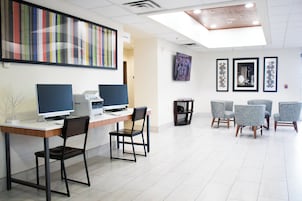 Un espacio de oficina moderno con un mostrador de recepción, computadoras y una zona de estar con sillas.