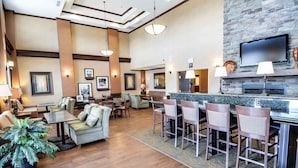 A spacious lobby with multiple seating areas, a bar, and a fireplace. - Hampton Inn & Suites Pinedale (Pinedale)