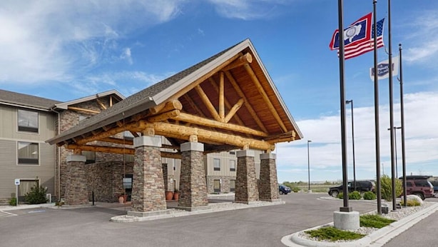 A lodge with a stone facade, a wooden covered entrance, and multiple flags. - Hampton Inn & Suites Pinedale (Pinedale)