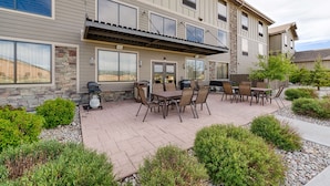 A multi-story building with a patio area featuring outdoor seating and a barbecue grill. - Hampton Inn & Suites Pinedale (Pinedale)