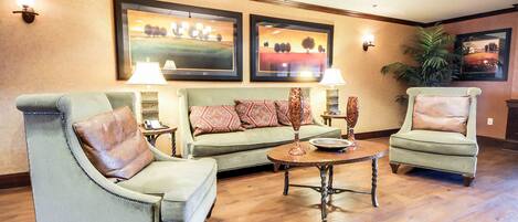 A living room with a green sofa set, two armchairs, a coffee table, and two wall-mounted lamps.