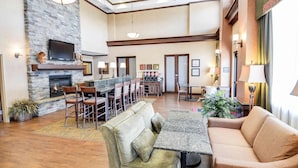A spacious hotel lobby with a stone fireplace, a bar area, and a seating area with a sofa and chairs. - Hampton Inn & Suites Pinedale (Pinedale)