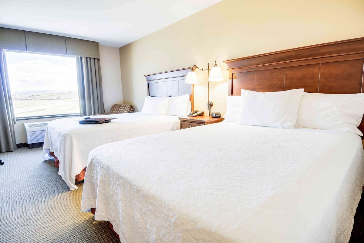 A hotel room with two beds, a large window, and a view of the landscape.