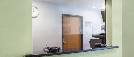 A reception desk with a clock, a door, and a counter with a card reader.