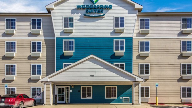 A multi-story hotel with a prominent sign reading "WOODSPRING SUITES". - WoodSpring Suites Houston Baytown (Baytown)