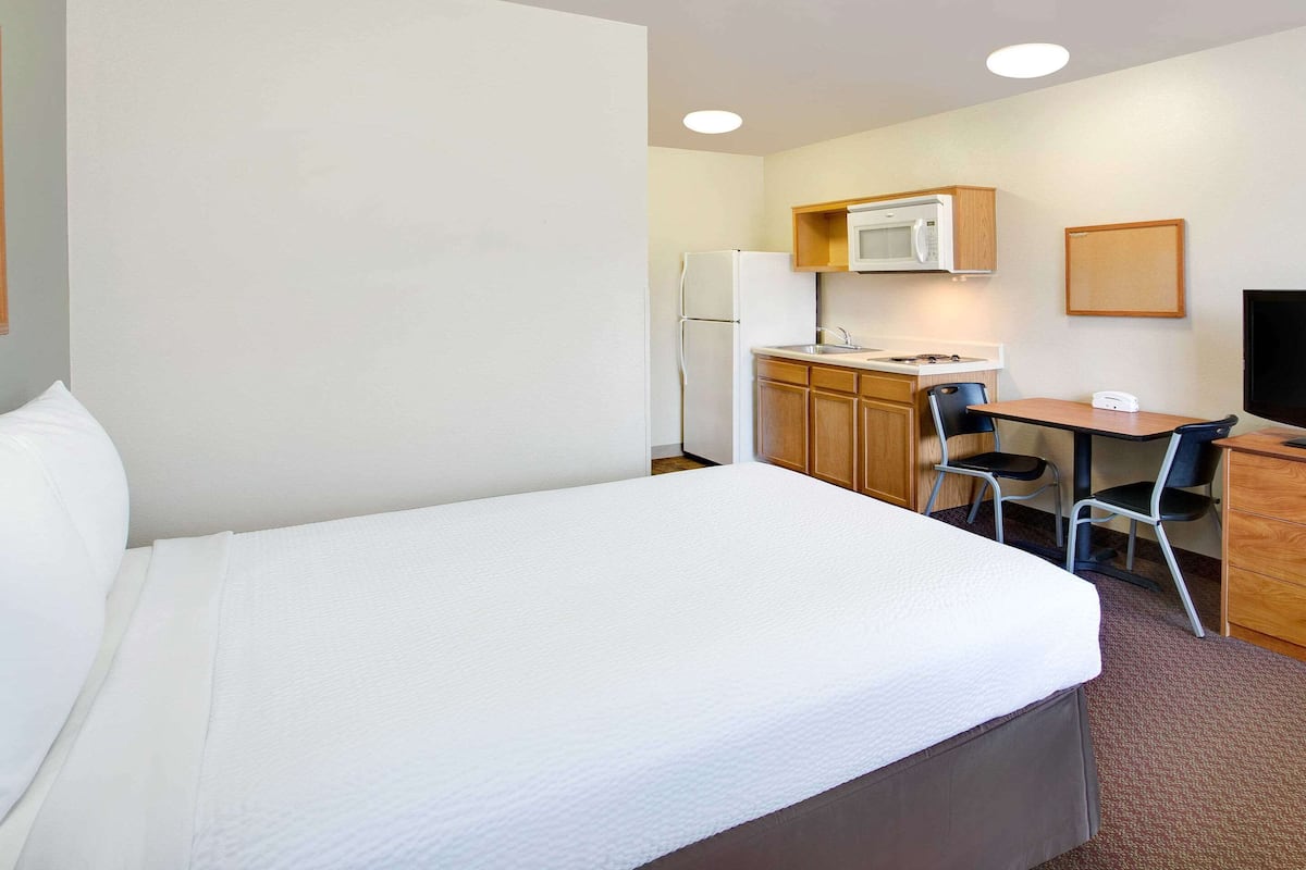 Une chambre d’hôtel équipée d’un lit, d’un bureau, d’une chaise, d’un four à micro-ondes, d’un réfrigérateur et d’une télévision.