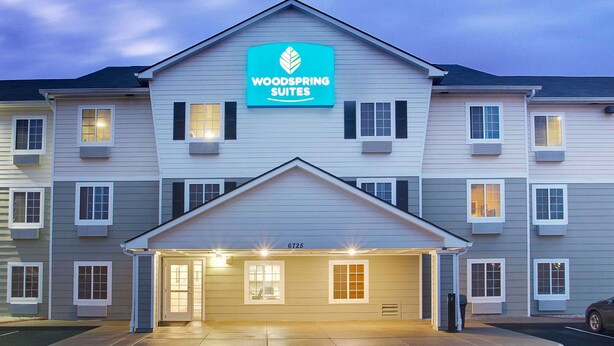 A multi-story hotel with a prominent sign reading "Woodspring Suites." - WoodSpring Suites Cincinnati Fairfield (Fairfield)