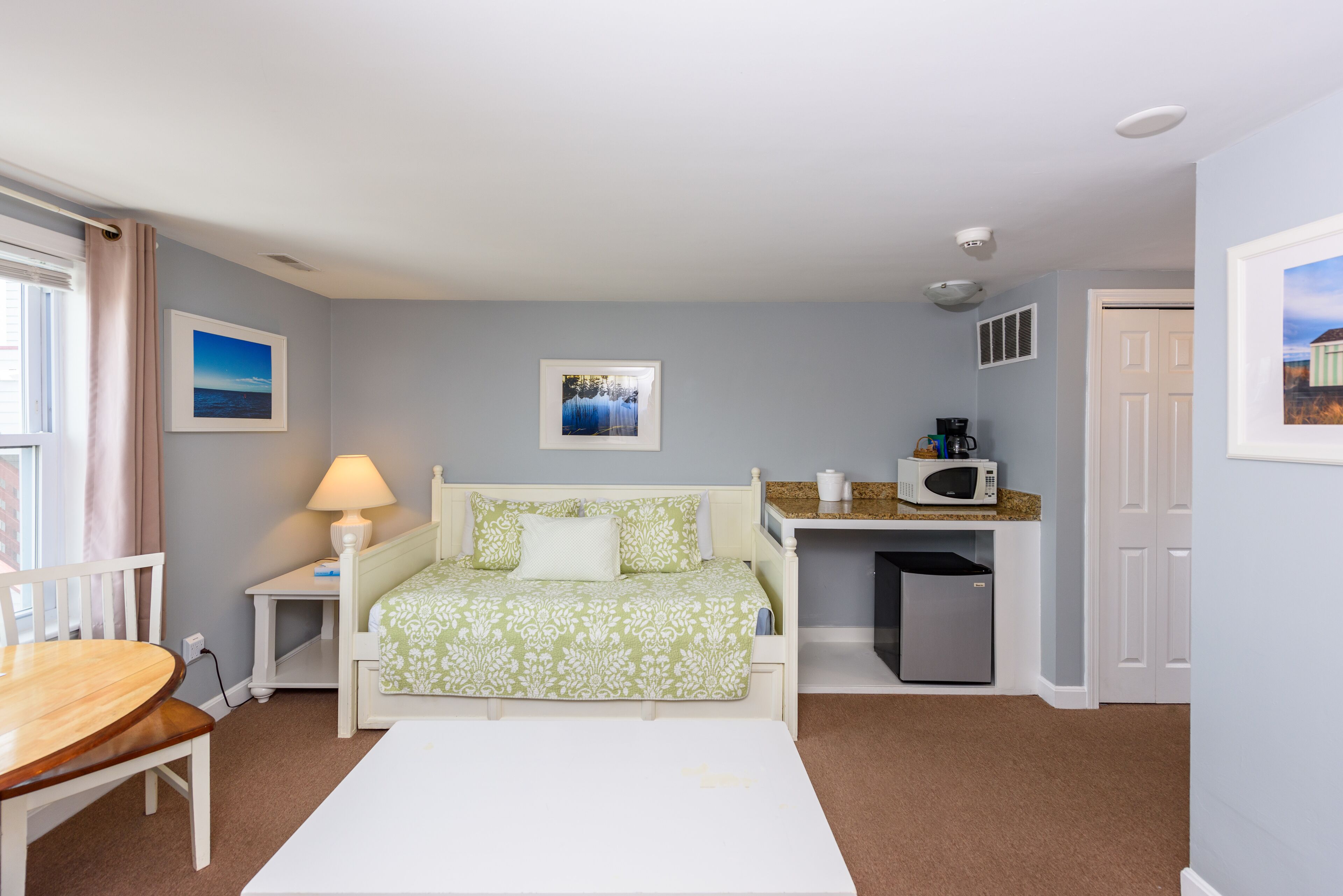 A bedroom with a bed, bedside table, lamp, and a view of the city.
