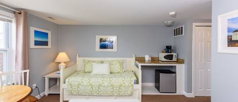 A bedroom with a bed, bedside table, lamp, and a view of the city.