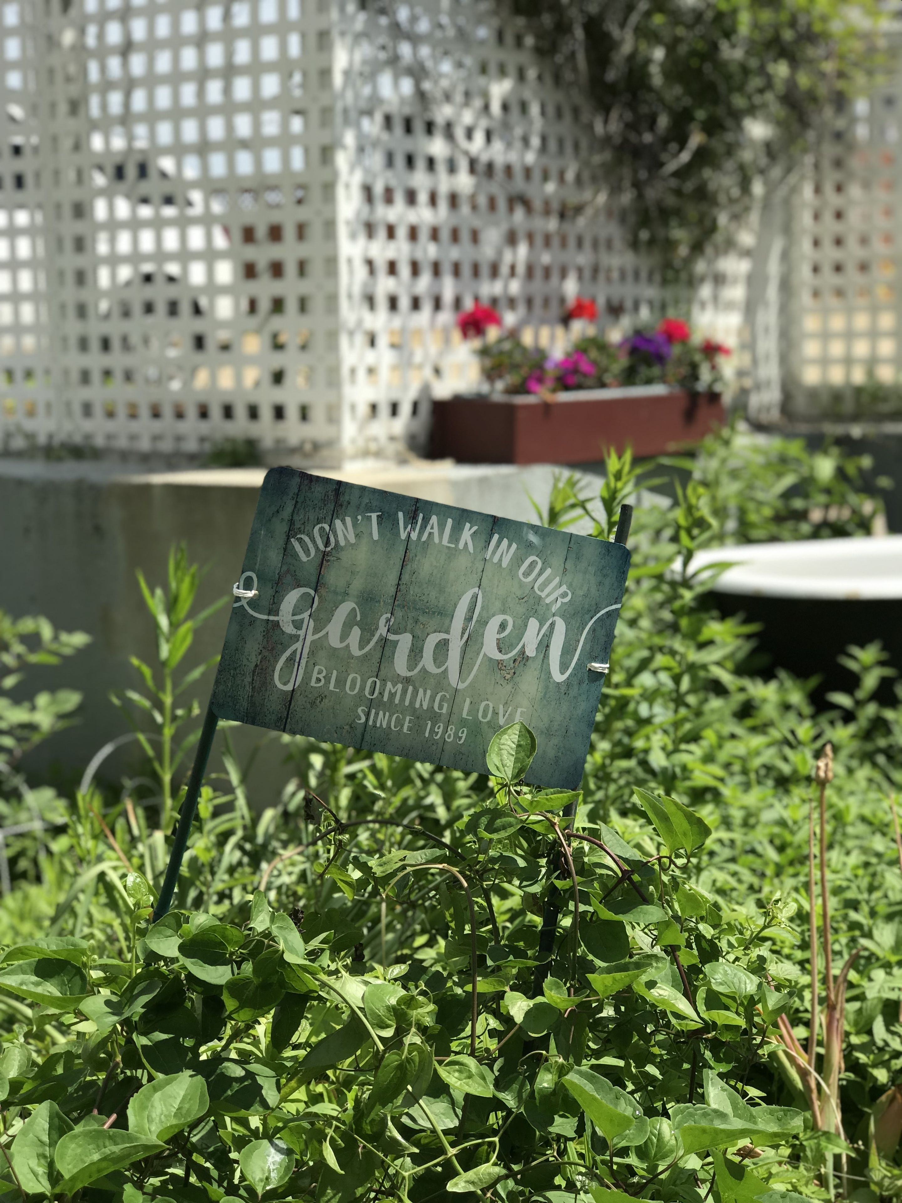 Een tuinbord met de tekst 'LOOP NIET DOOR ONZE TUIN BLOOMING LOVE SINCE 1989'.